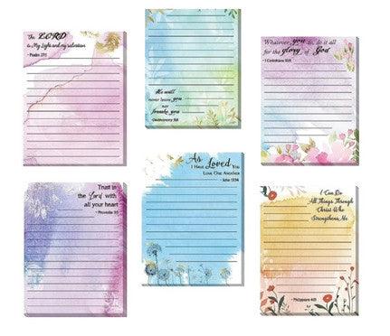 A set of six decorative notepads, each with a different pastel-colored design and inspirational Bible verse at the top. The designs feature floral and nature-themed backgrounds in shades of purple, blue, green, and pink. The lined notepads are perfect for jotting down notes, prayers, or daily reflections.