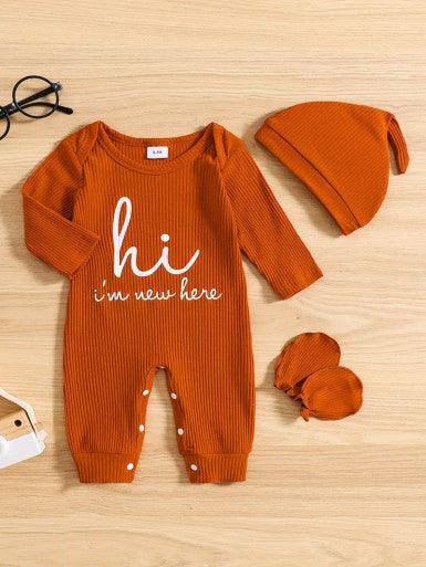 A cute baby Long Sleeve Baby Romper in Burnt Orange accompanied by a matching hat and mittens, showcasing a cheerful and playful outfit displaying the text "Hi, I'm new here."