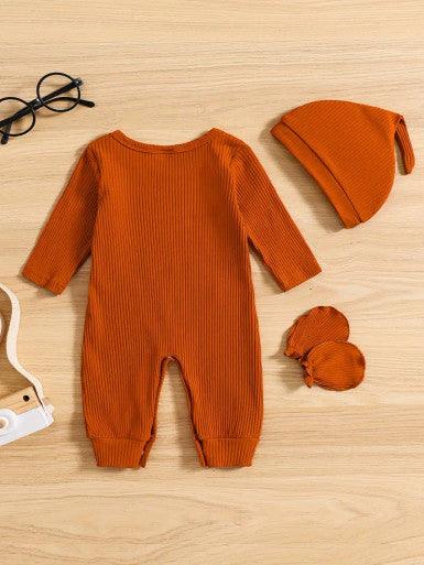 A cute baby Long Sleeve Baby Romper in Burnt Orange accompanied by a matching hat and mittens, showcasing a cheerful and playful outfit displaying the text "Hi, I'm new here."