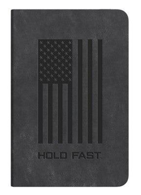 A black journal with an embossed American flag design on the cover. The words "HOLD FAST" are printed below the flag in bold letters. The journal has a sleek and minimalist appearance, ideal for note-taking, journaling, or as a statement accessory.