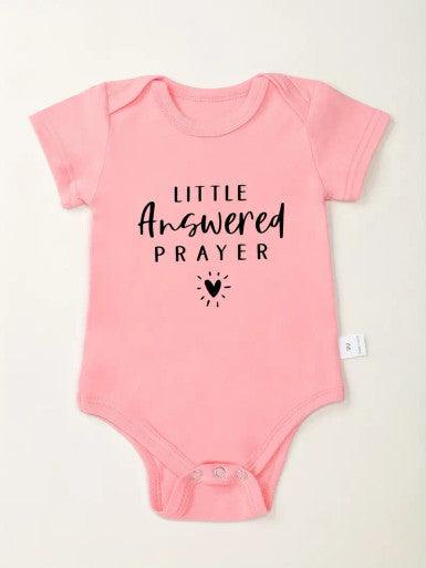 A cute short sleeve baby pink romper showcasing the text "little answered prayer", symbolizing joy and love for a newborn child.