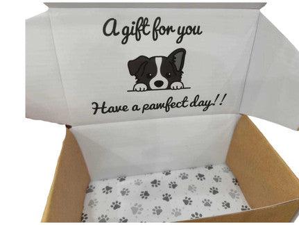 An open gift box with a playful design on the inside lid. The lid features a cute illustration of a dog peeking over a ledge with the text "A gift for you" above it and "Have a pawfect day!!" below. The bottom of the box is lined with paper featuring a paw print pattern, adding a charming and themed touch to the packaging, perfect for pet-related gifts or for dog lovers.