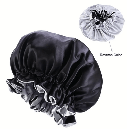 A reversible satin bonnet with one side in sleek black and the other in light gray. The bonnet features a ruffled edge that adds a stylish touch, while the smooth satin material is designed to protect hair from breakage and frizz. The reversible design offers versatility, allowing the wearer to choose between the black or gray side depending on their preference.