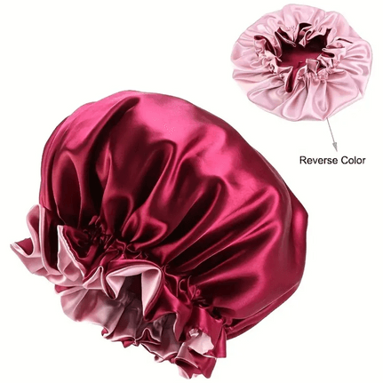 A reversible satin bonnet with one side in vibrant burgundy and the other in soft pink. The bonnet features a ruffled edge for a stylish look, while the smooth satin material helps protect hair from breakage and frizz. The reversible design allows for flexibility in style, giving the option to wear either the burgundy or pink side outward.