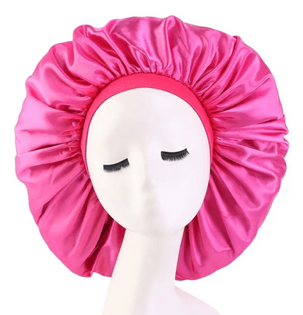 A vibrant pink satin bonnet showcased on a mannequin head with closed eyes. The bonnet features a glossy, smooth finish, designed to protect hair while sleeping. The elastic band around the edge is also pink, providing a secure and comfortable fit. The satin material helps reduce friction, retain moisture, and minimize hair breakage, making it ideal for maintaining healthy hair. This bonnet combines functionality with a bold, stylish appearance, suitable for all hair types.