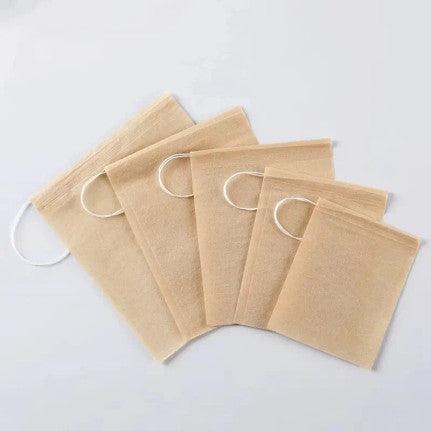 A set of five reusable tea filter bags made from beige, unbleached fabric. Each bag features a drawstring closure, allowing easy access to fill with loose leaf tea or herbs. These eco-friendly tea bags are designed for steeping tea, providing an alternative to disposable tea bags while allowing for a customizable tea-drinking experience. The material has a natural, earthy appearance, emphasizing sustainability and convenience.