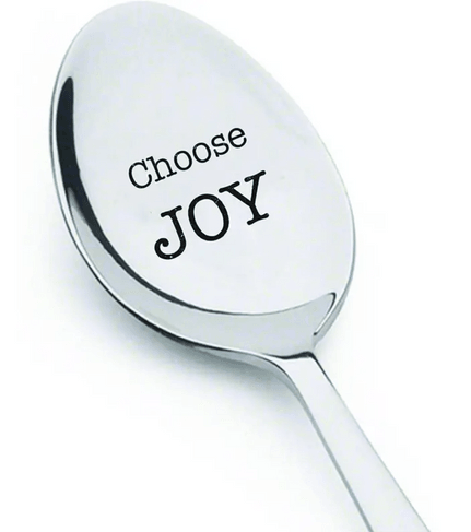 This image features a shiny, polished silver spoon with the inspirational phrase "Choose JOY" engraved on the bowl. The text is in black, with "Choose" in a smaller, classic font and "JOY" in a larger, bold font, emphasizing the message. The spoon has a smooth, reflective surface, highlighting its elegant and clean design. This spoon could be used as a motivational gift item, adding a positive reminder to daily routines.