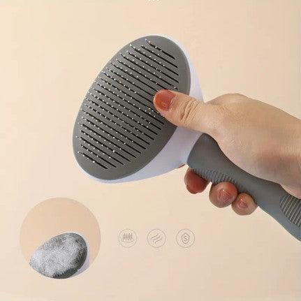 The image shows a pet grooming brush against a light blue background. The brush features a wide, rectangular head with closely spaced metal bristles designed for removing loose fur and detangling. The ergonomic handle is gray with a textured grip for comfortable use. The brush's dimensions are indicated, with a width of 11 cm (4.33 inches) and a length of 21 cm (8.26 inches). The brush is positioned upright, leaning against a white step-like object.